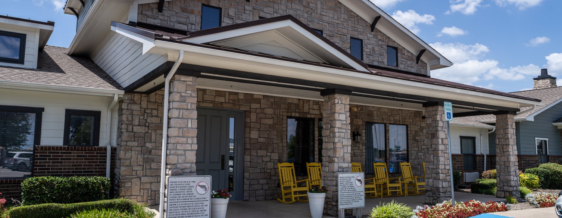 a clubhouse entrance with yellow rocking chairs in front 