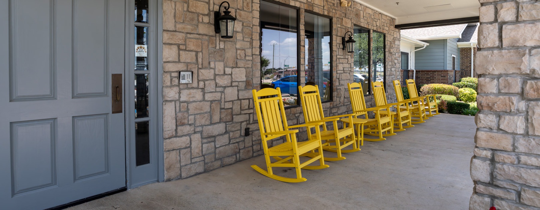 a row of yellow rocking chairs near an entrance to a building