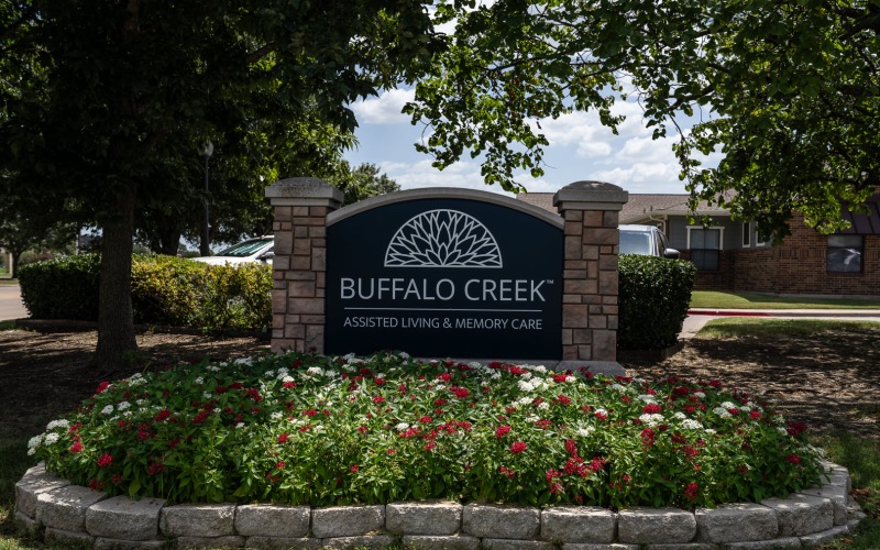 a sign with a flower bed in front of it